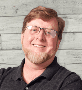 Ron Kline headshot in front of a wood textured wall.