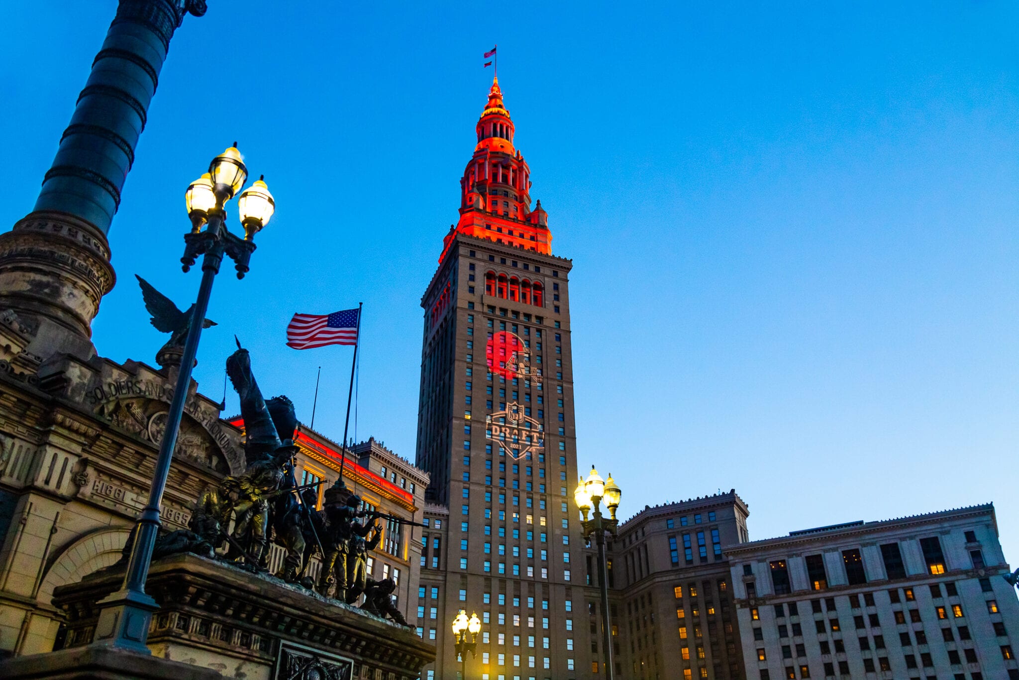 An upwards camera angle of a tall building lit up with red lights at the top.