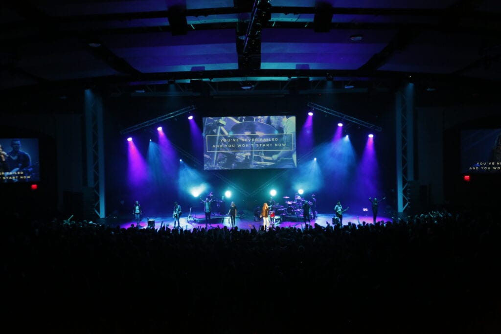 Worship Concert stage with nine performers lit by blue and purple lights.