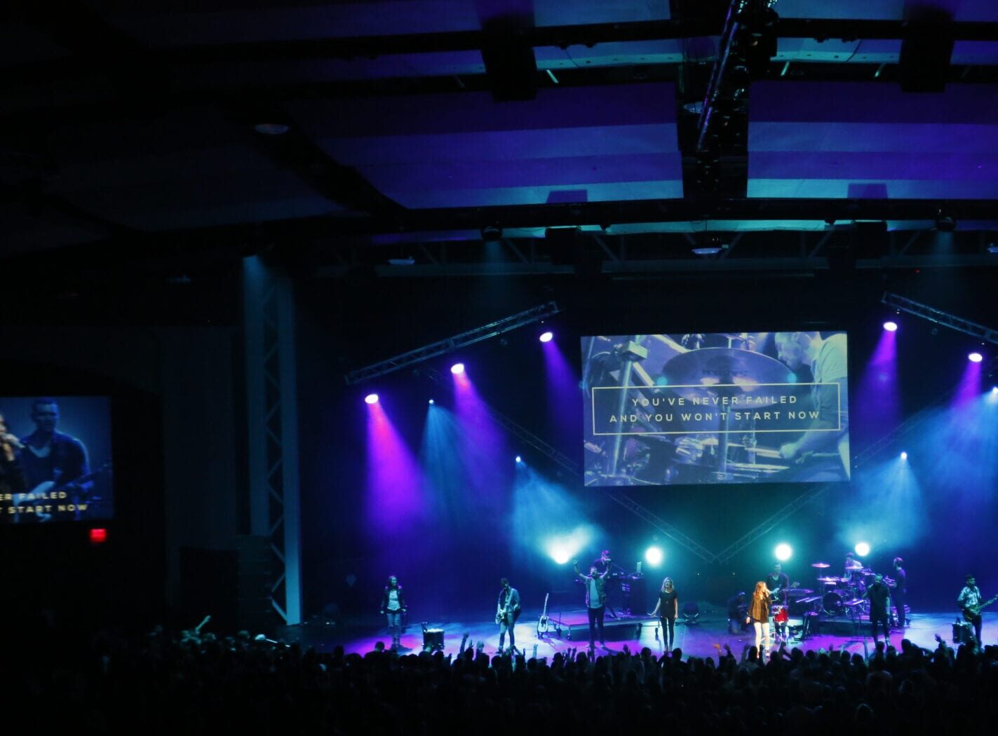 Worship Concert stage with nine performers lit by blue and purple lights.