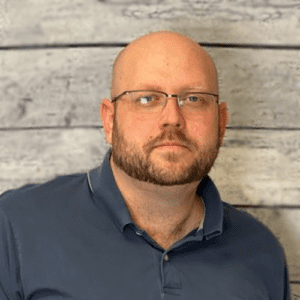 Matt White headshot in front of a wood textured wall.