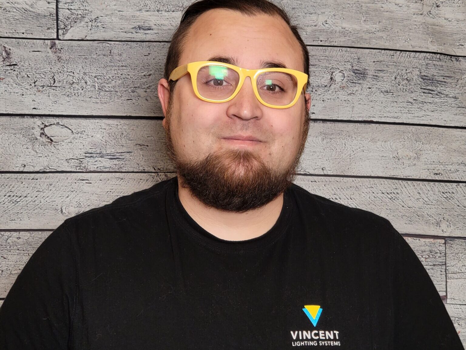 Bryan Mravec headshot in front of a wood textured wall.