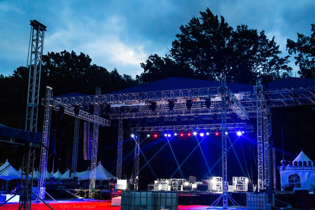 Performance stage outdoors at night with red and blue lights.