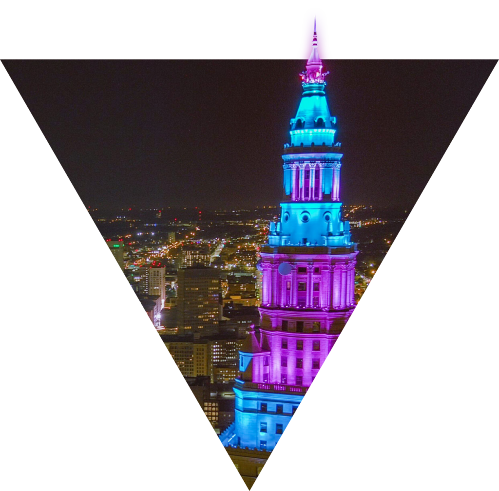 Top of a building lit up with blue and purple lights overlooking a city at night.