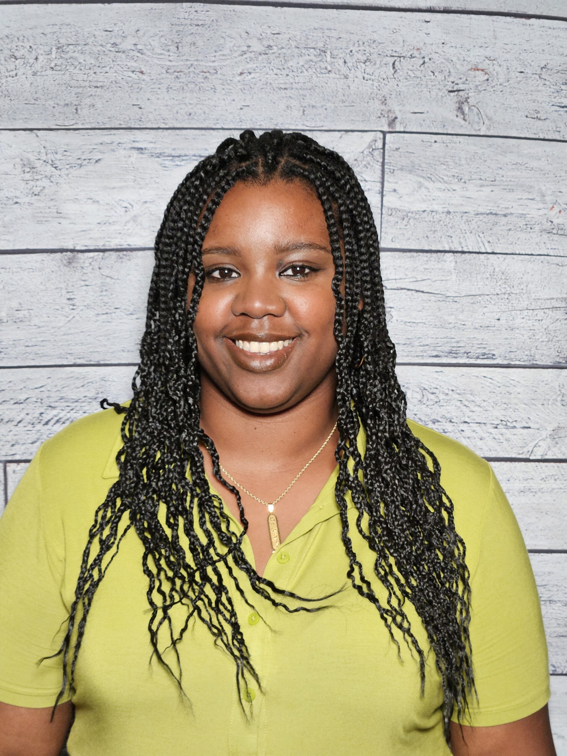 Taylor Wheeler headshot, standing in front of wood textured wall.