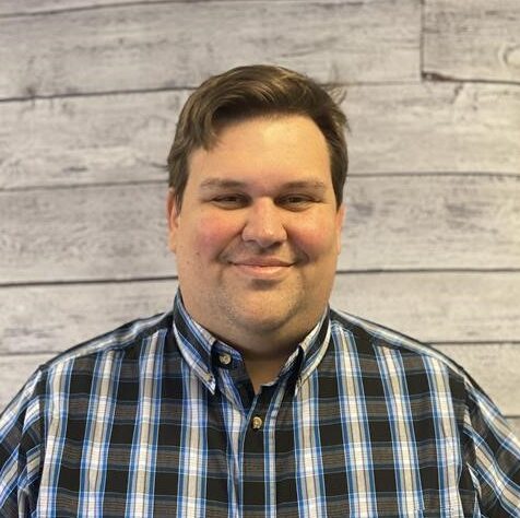 Zach Kappesser headshot, standing in front of wood textured wall