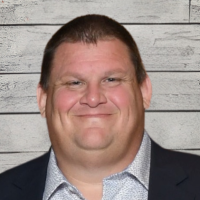 Adam Hayward headshot with wood panel background