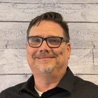 Corey Harrison headshot on wood panel background